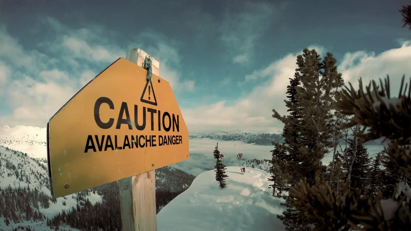 Yellow caution warning sign in a snowy mountain landscape