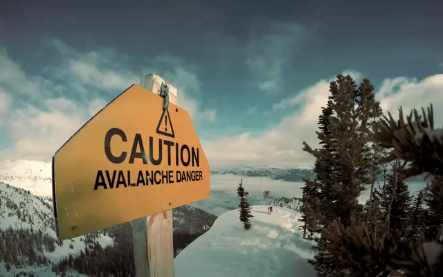 Yellow caution warning sign in a snowy mountain landscape
