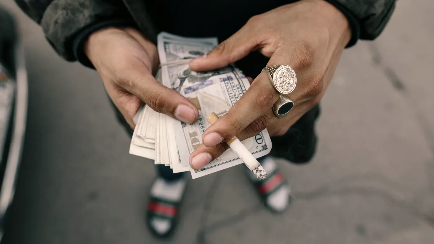 Hands counting a small stack of banknotes