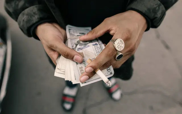 Hands counting a small stack of banknotes