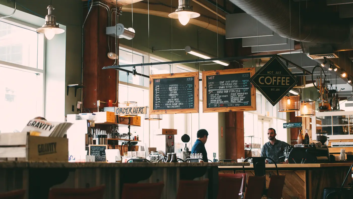 Busy coffee shop with staff behind the counter and customers at tables