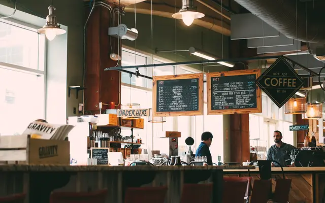 Busy coffee shop with staff behind the counter and customers at tables