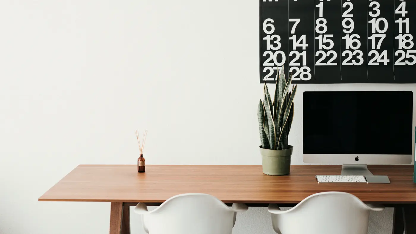 Minimal desk with a computer beneath a large wall calendar