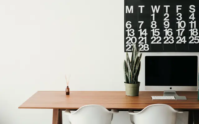 Minimal desk with a computer beneath a large wall calendar