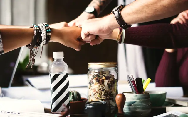 Team members bumping fists over a desk