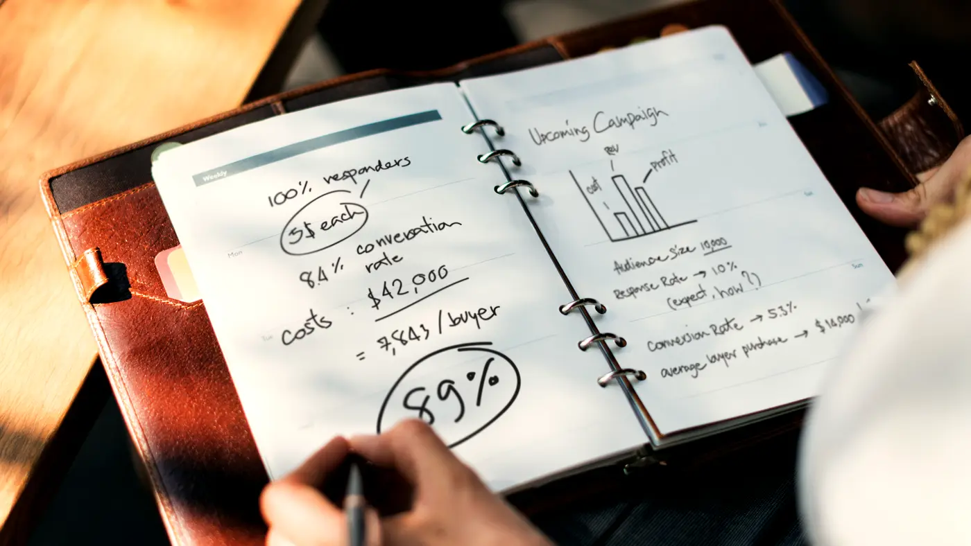 Hand writing figures and percentages in a planning notebook