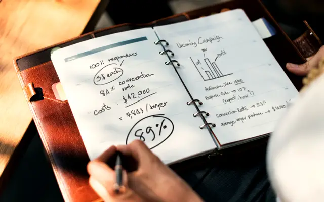 Hand writing figures and percentages in a planning notebook