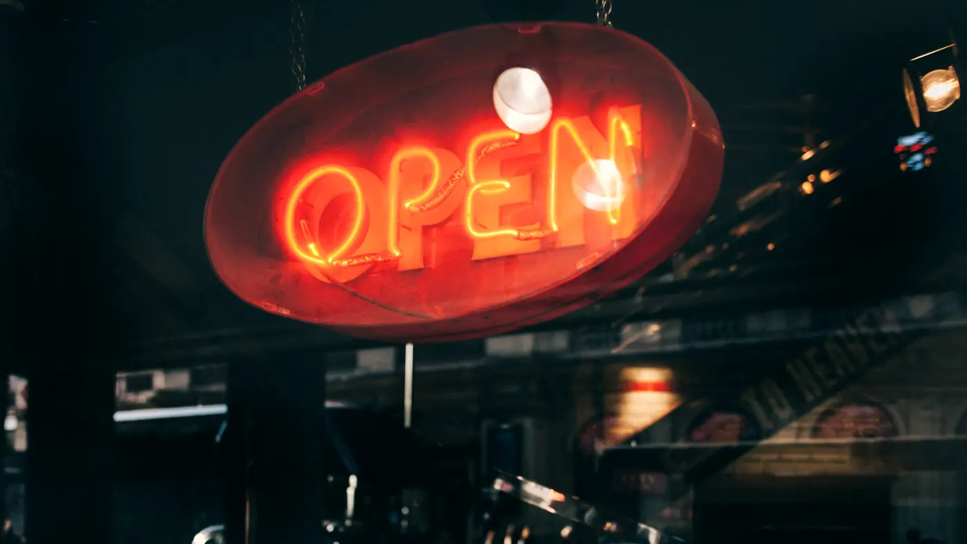 Red neon OPEN sign glowing in a shop window at night