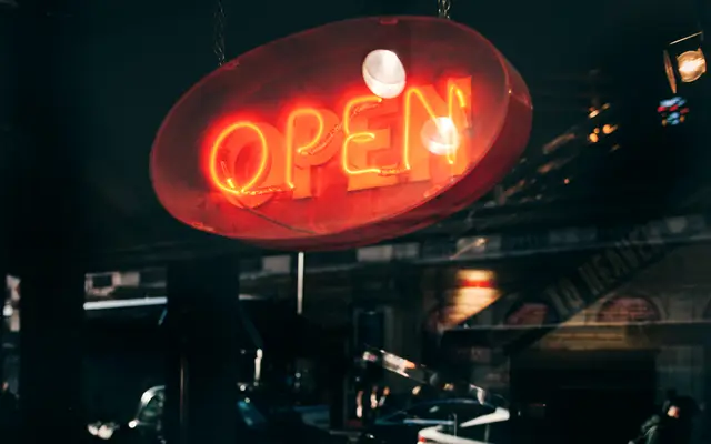 Red neon OPEN sign glowing in a shop window at night