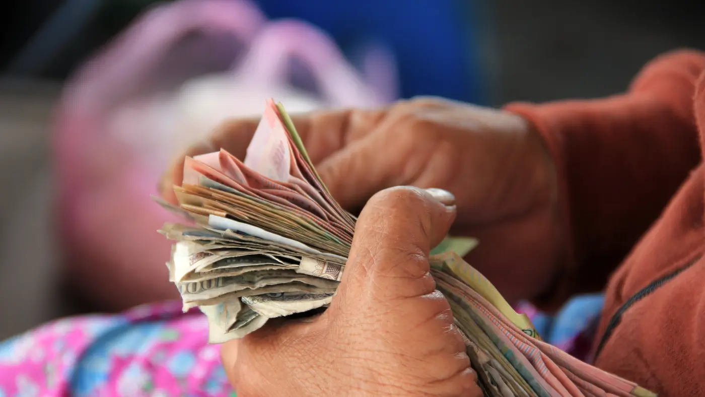 Hands counting a thick stack of paper banknotes