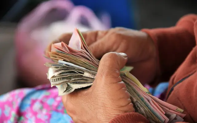Hands counting a thick stack of paper banknotes