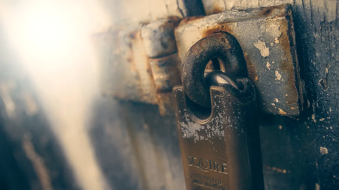 Close-up of an old padlock on a metal door