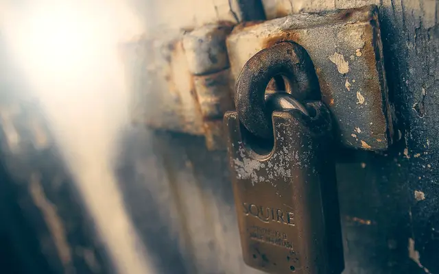 Close-up of an old padlock on a metal door