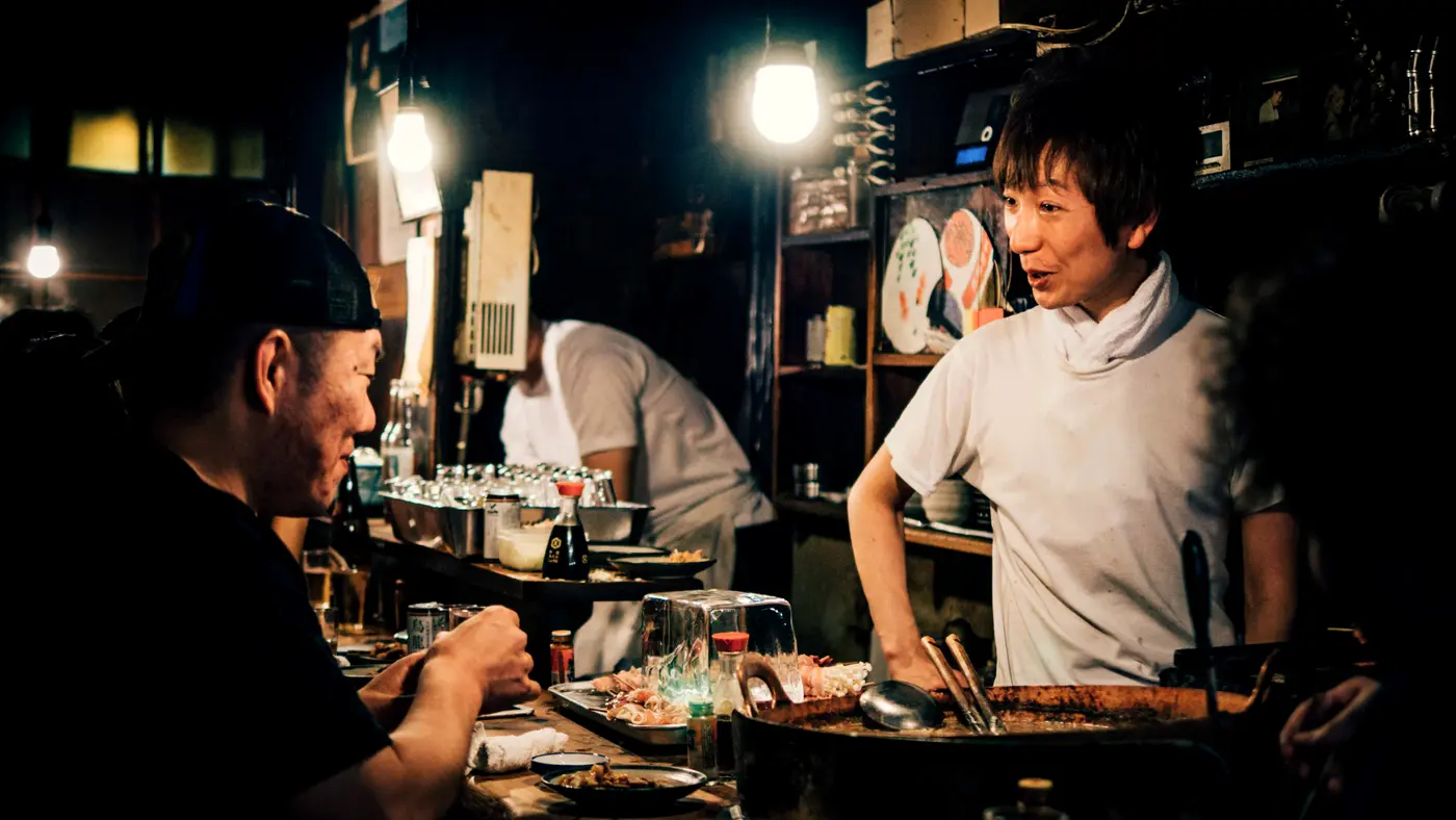 Cook talking with customers across the counter of a small restaurant