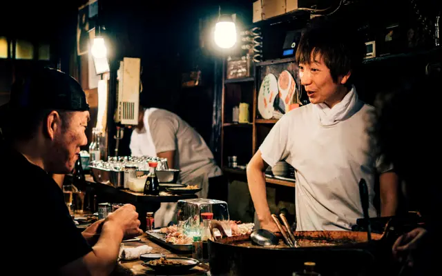 Cook talking with customers across the counter of a small restaurant