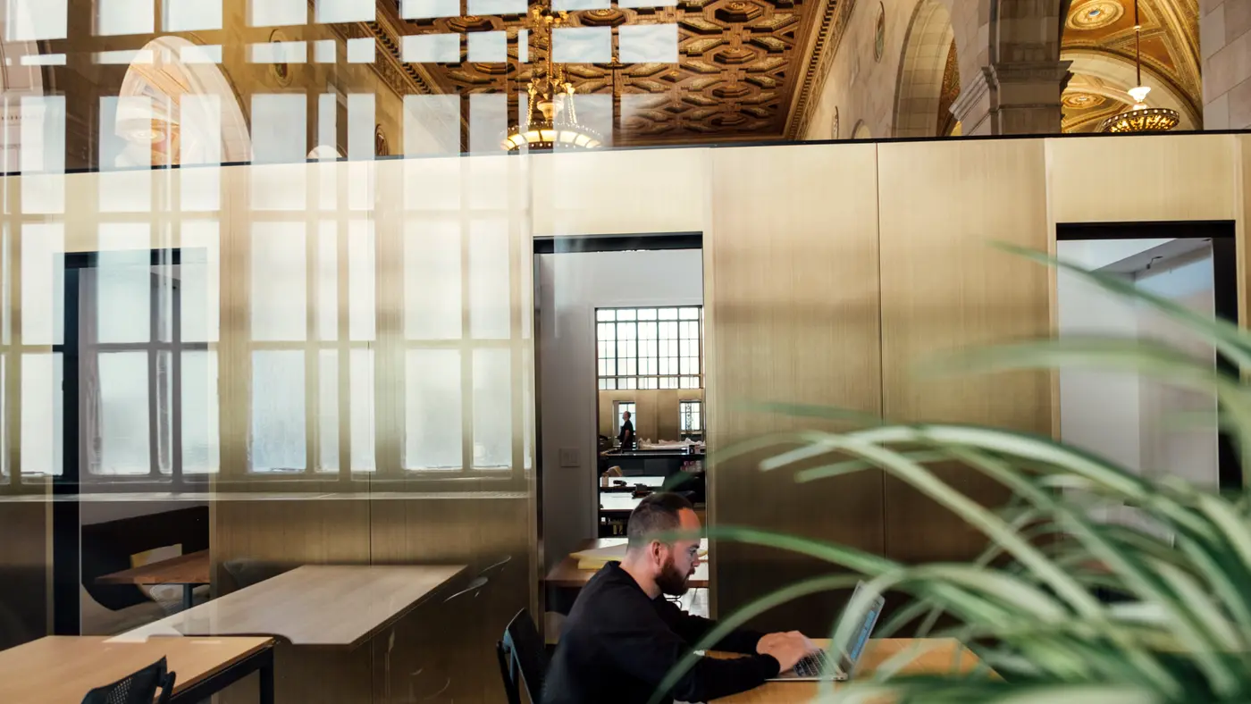 Man working at a desk in a modern office with plants