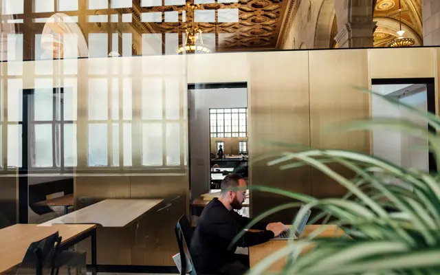Man working at a desk in a modern office with plants
