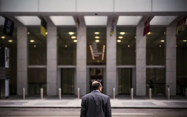 Man in a suit walking toward the entrance of an office building