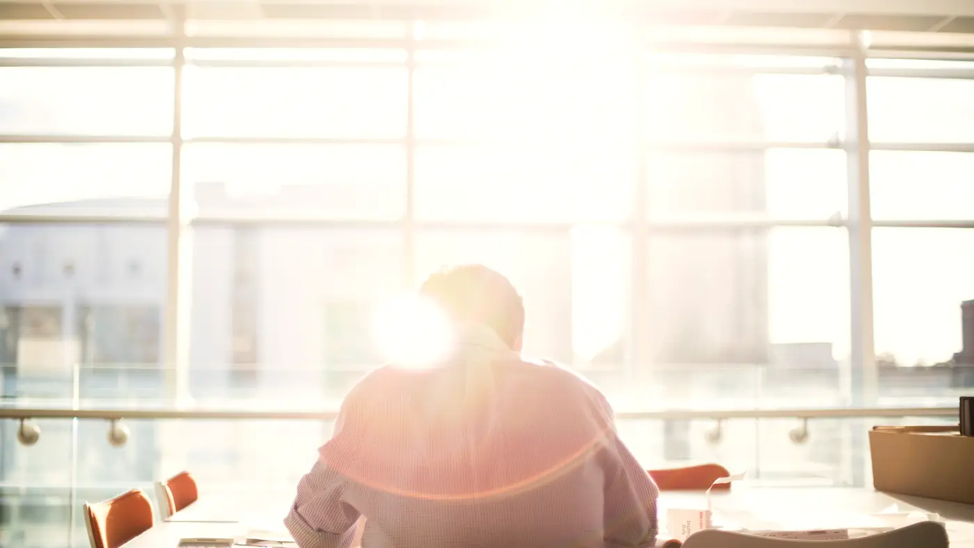 Man sitting at a desk in front of a bright window