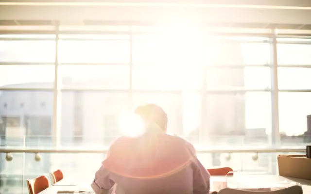 Man sitting at a desk in front of a bright window