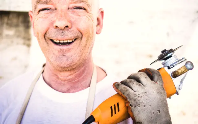 Smiling worker in an apron holding a power tool