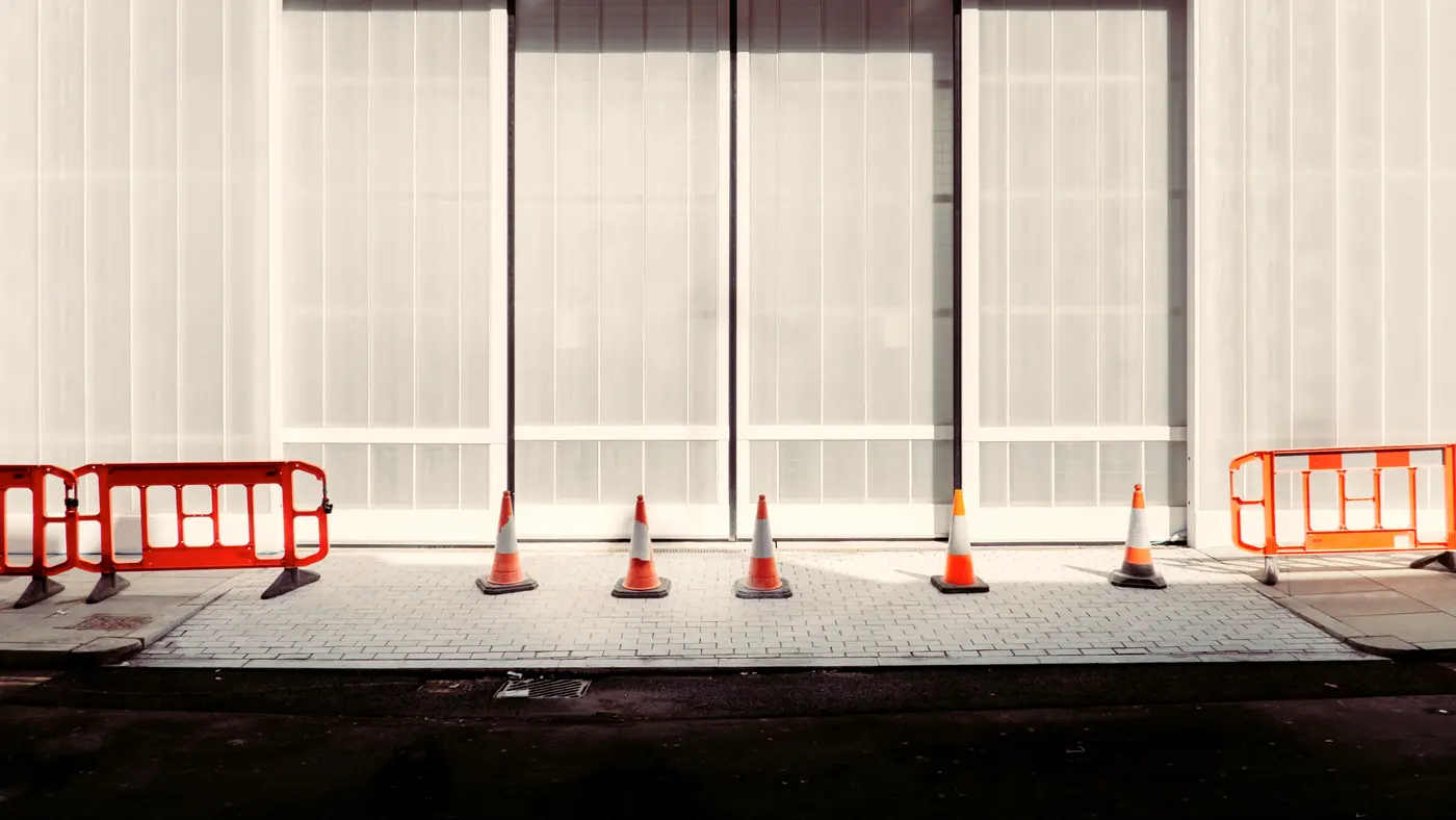 Row of orange barriers and traffic cones in front of a building
