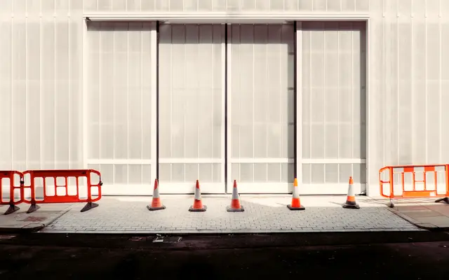 Row of orange barriers and traffic cones in front of a building