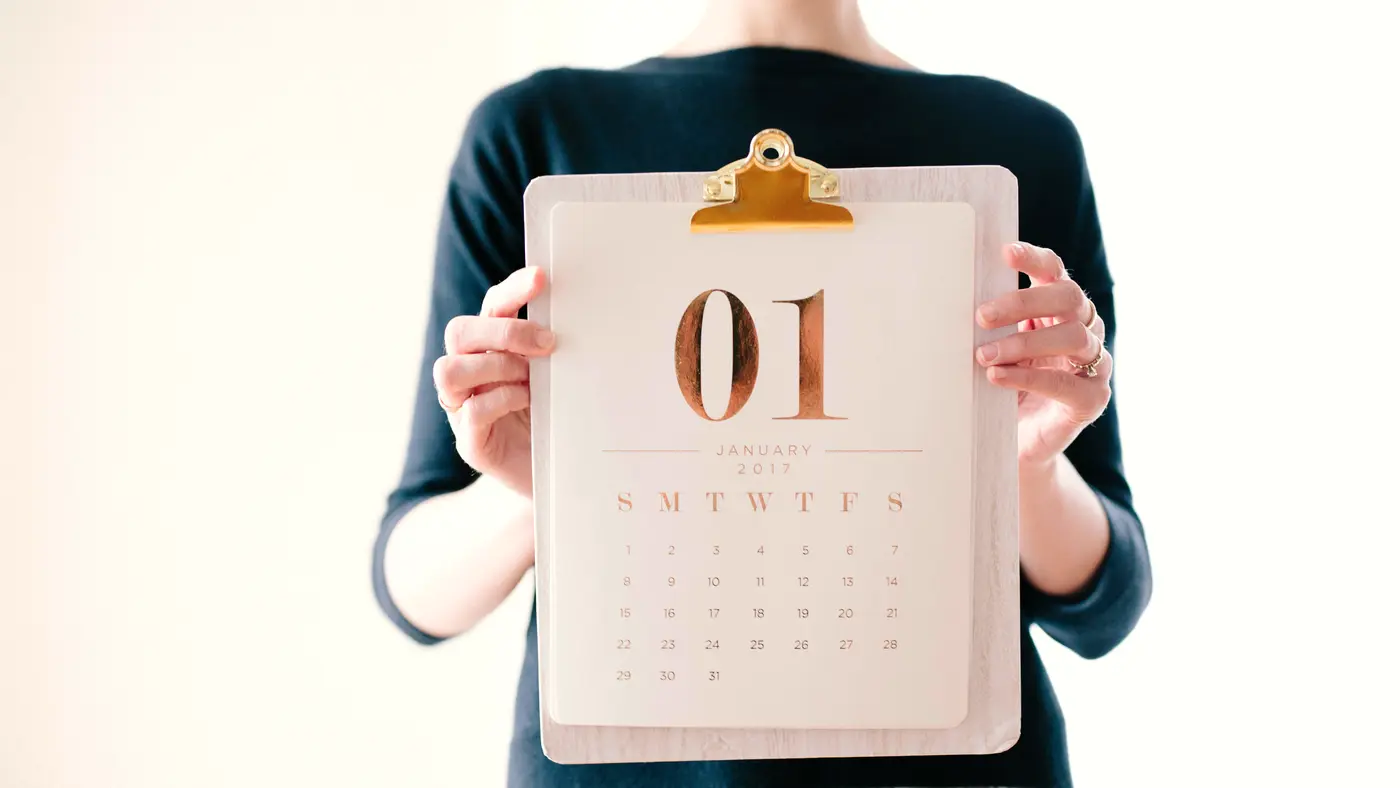 Person holding a clipboard with a calendar page showing day 01