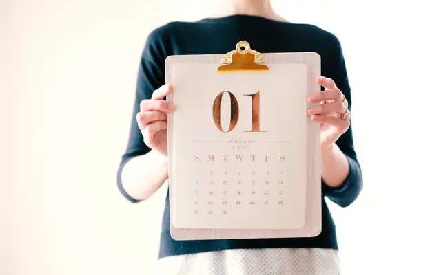 Person holding a clipboard with a calendar page showing day 01