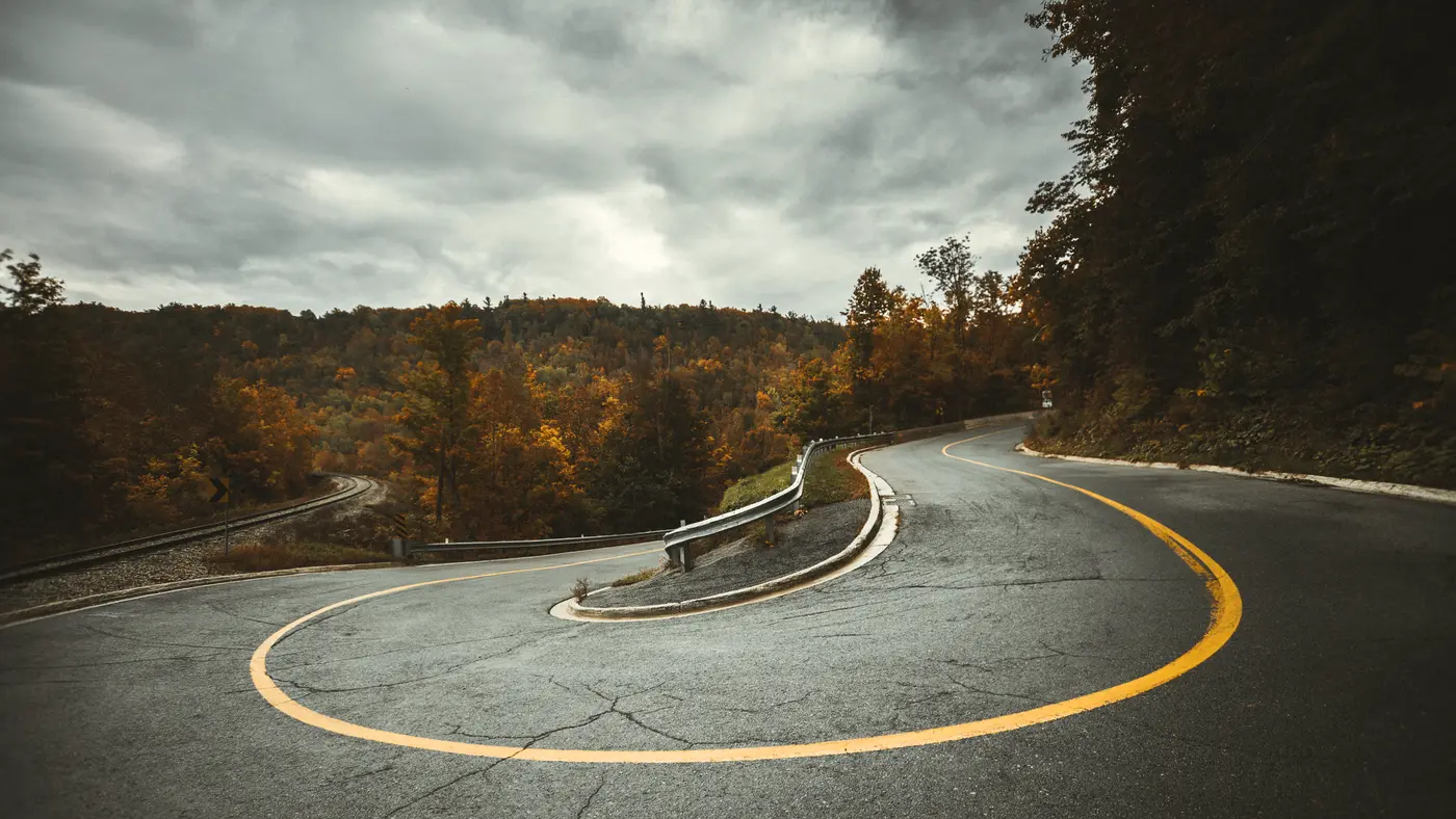Aerial view of a road making a tight hairpin turn through the forest