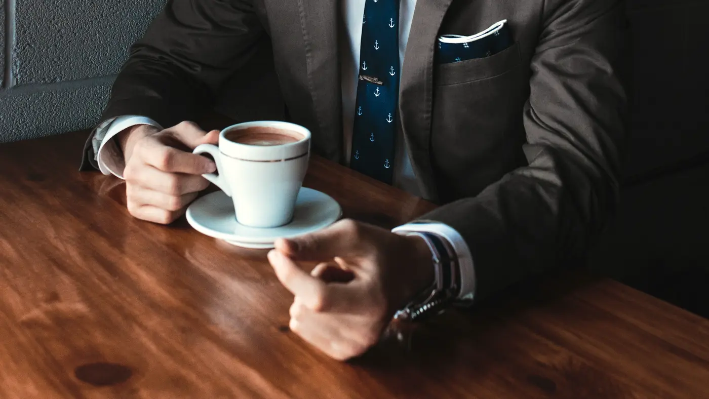 Businessman in a suit with a cup of coffee at a wooden table