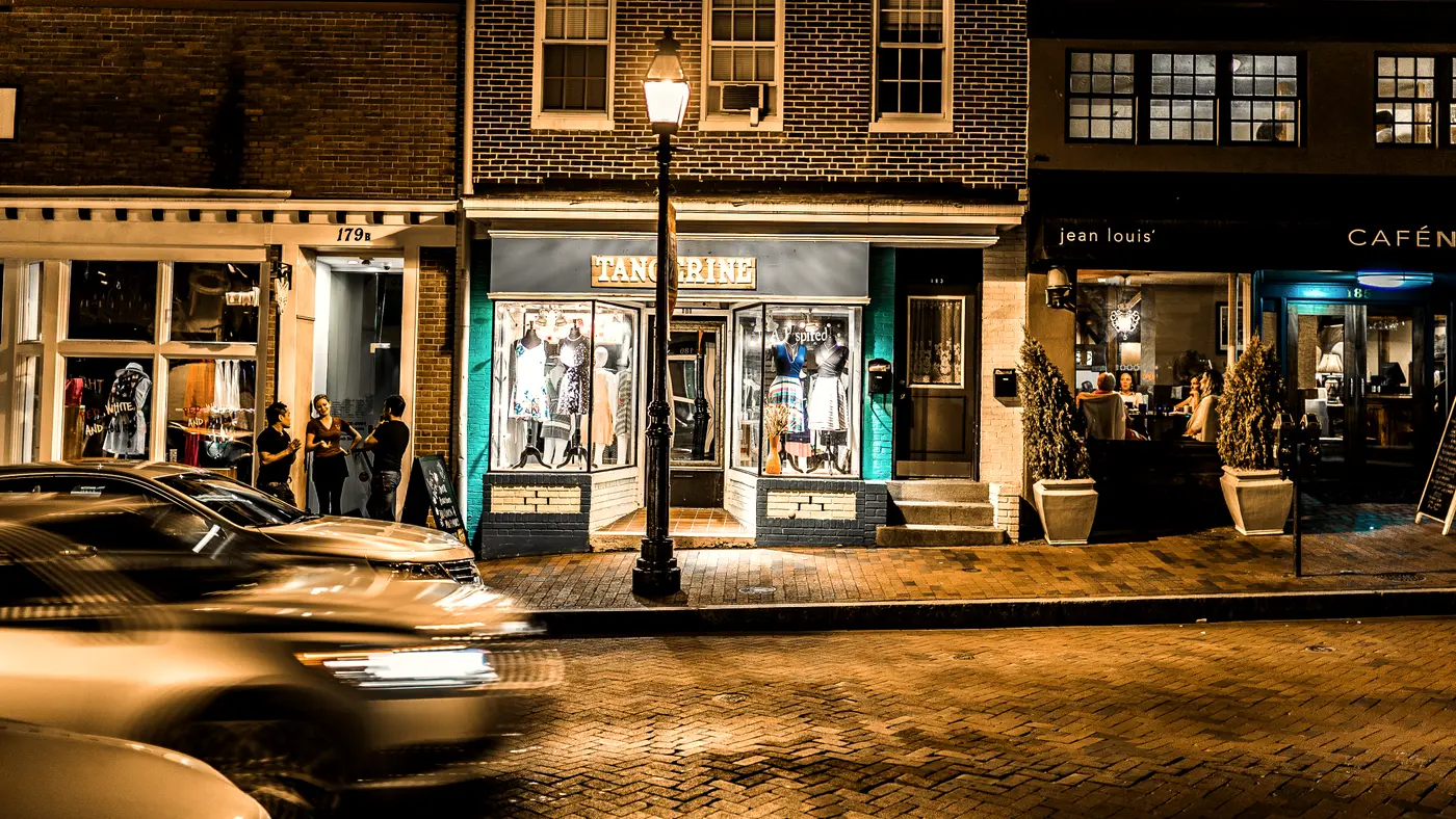Row of lit brick storefronts on a main street at night