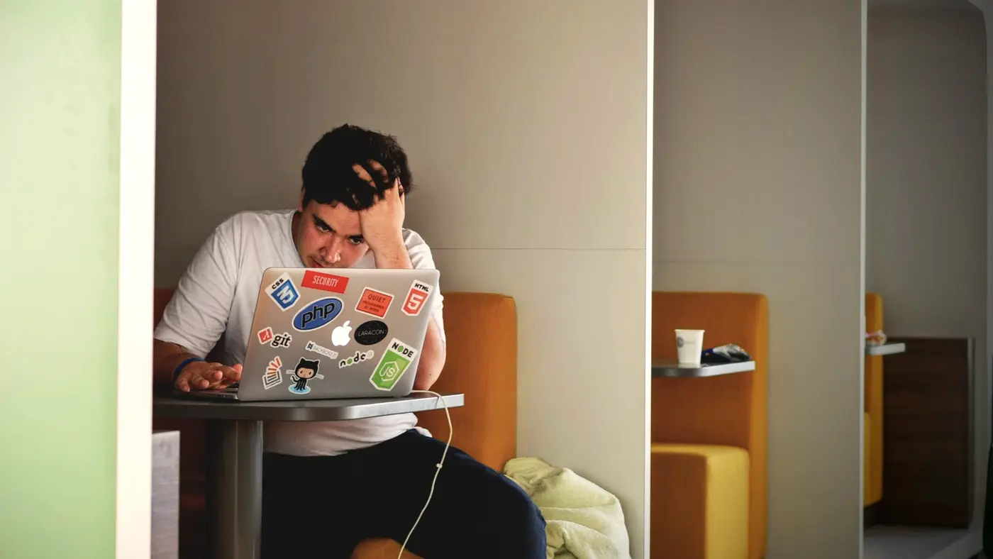 Man holding his head in frustration while working on a laptop