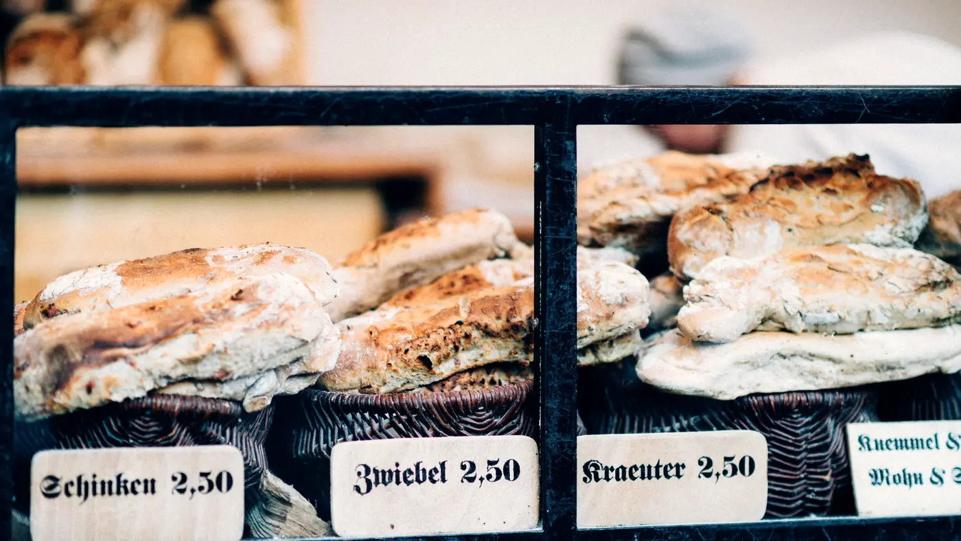 Bakery display case with loaves labeled with handwritten price cards