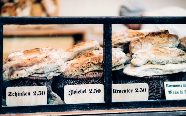 Bakery display case with loaves labeled with handwritten price cards