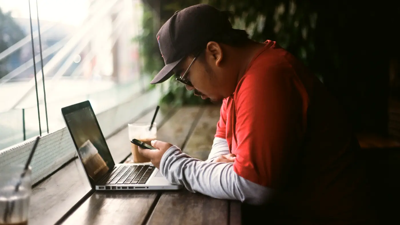 Man writing notes in a notebook next to a laptop