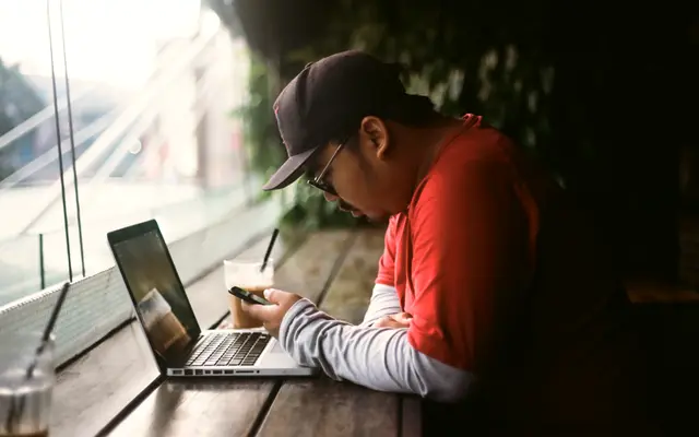Man writing notes in a notebook next to a laptop