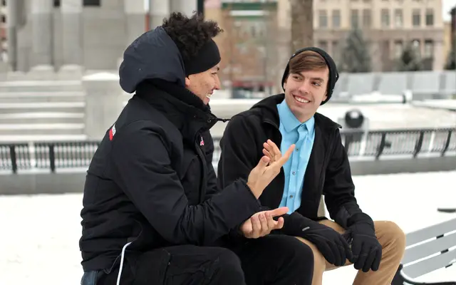 Two men talking on a bench outdoors in winter