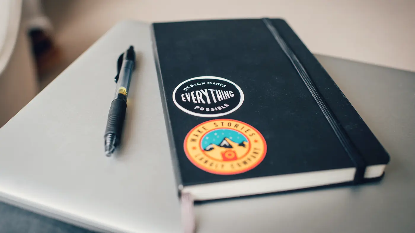 Black notebook and pen resting on a laptop