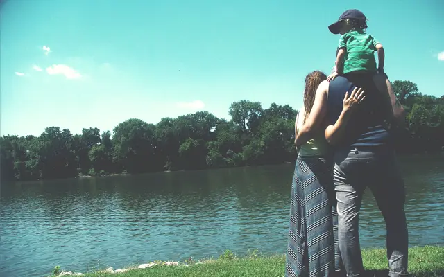 Father carrying a child on his shoulders beside a lake