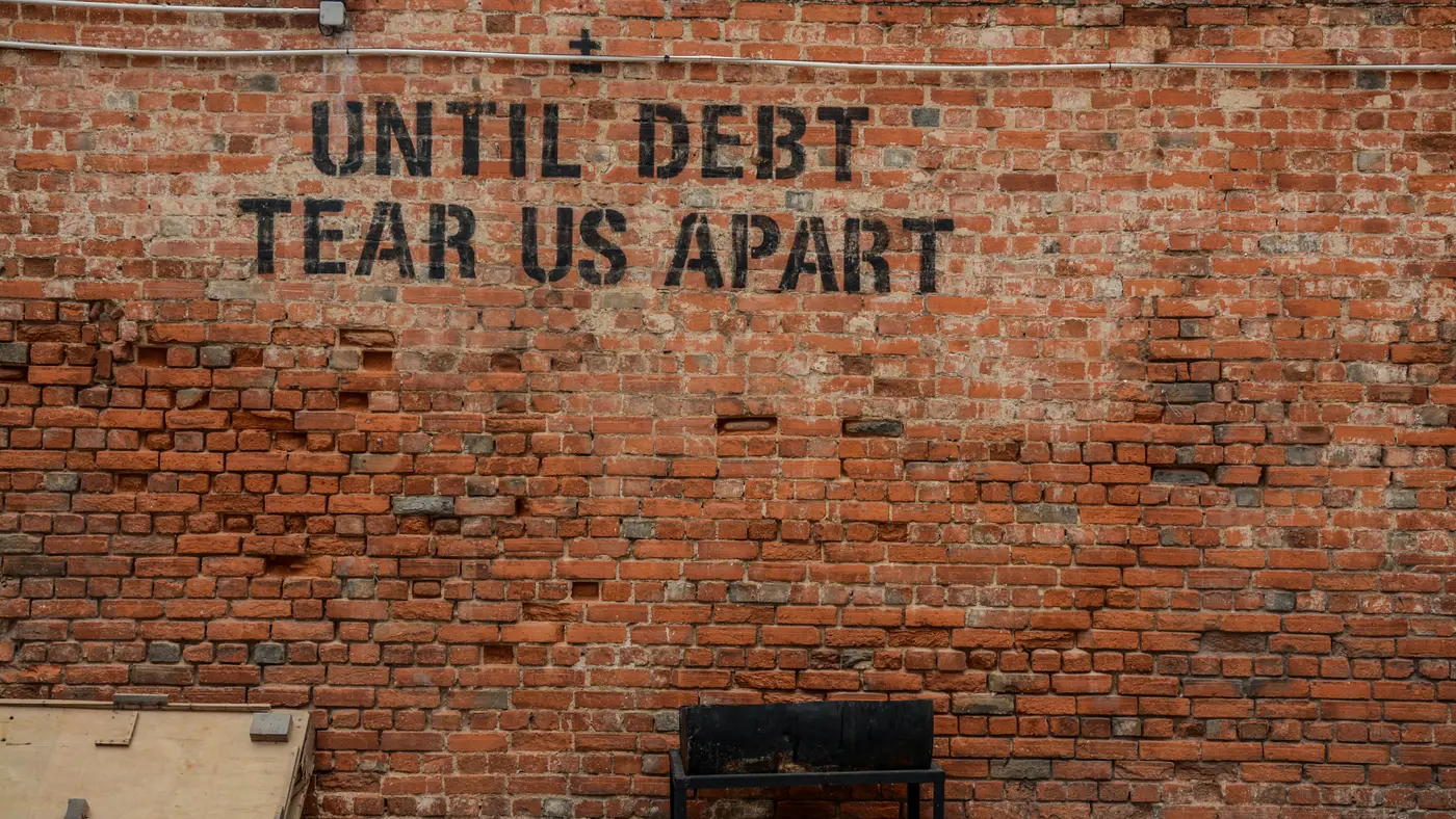 Brick wall painted with the words Until Debt Tear Us Apart