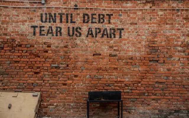 Brick wall painted with the words Until Debt Tear Us Apart