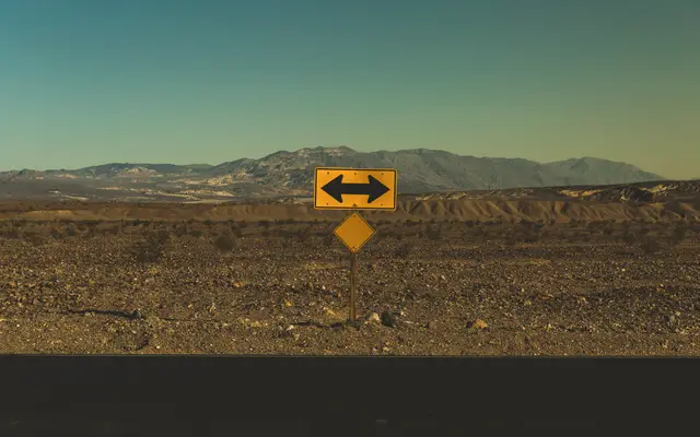 Two-way arrow road sign standing alone in a desert valley
