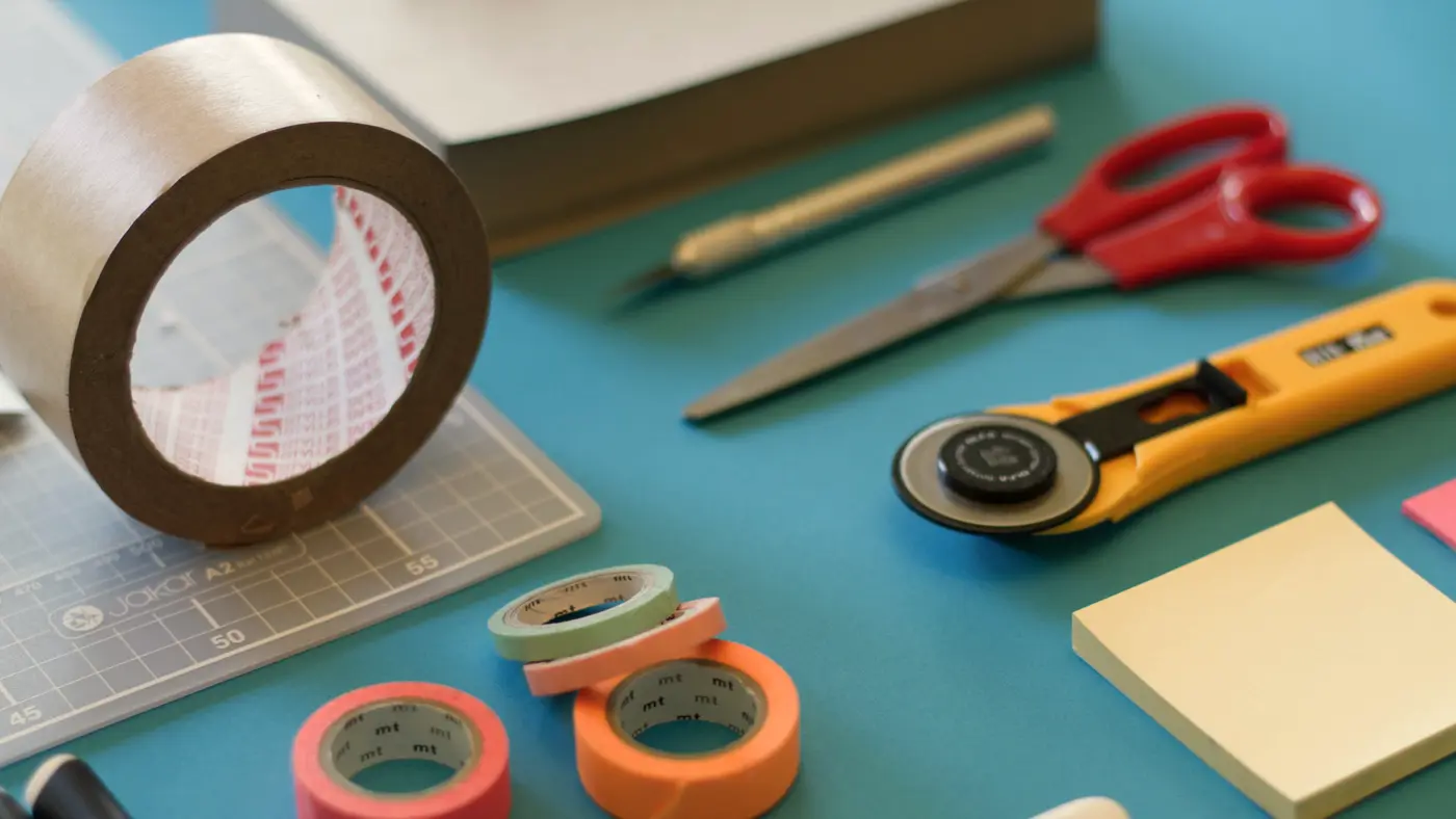 Tape, scissors, sticky notes and craft tools laid out on a table