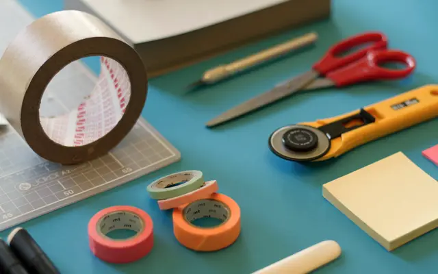Tape, scissors, sticky notes and craft tools laid out on a table