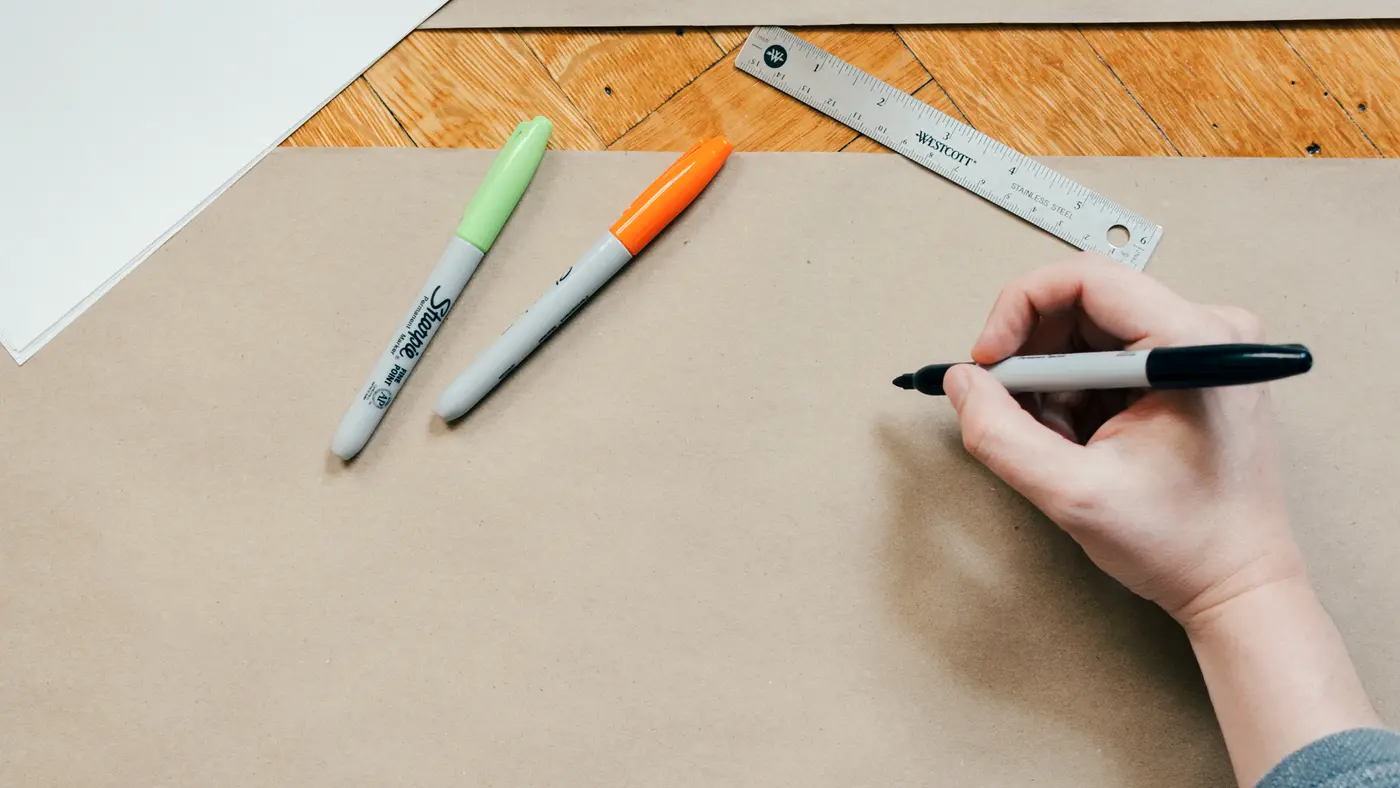 Hand drawing with a marker beside a ruler on brown paper