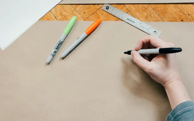 Hand drawing with a marker beside a ruler on brown paper