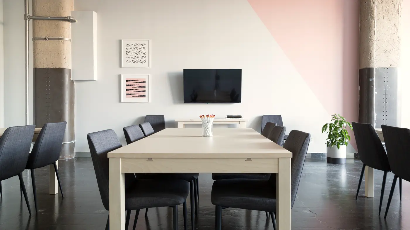 Meeting table with chairs in a bright room with a pink accent wall