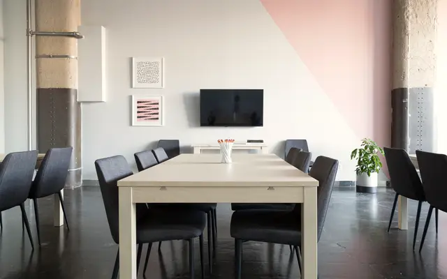 Meeting table with chairs in a bright room with a pink accent wall