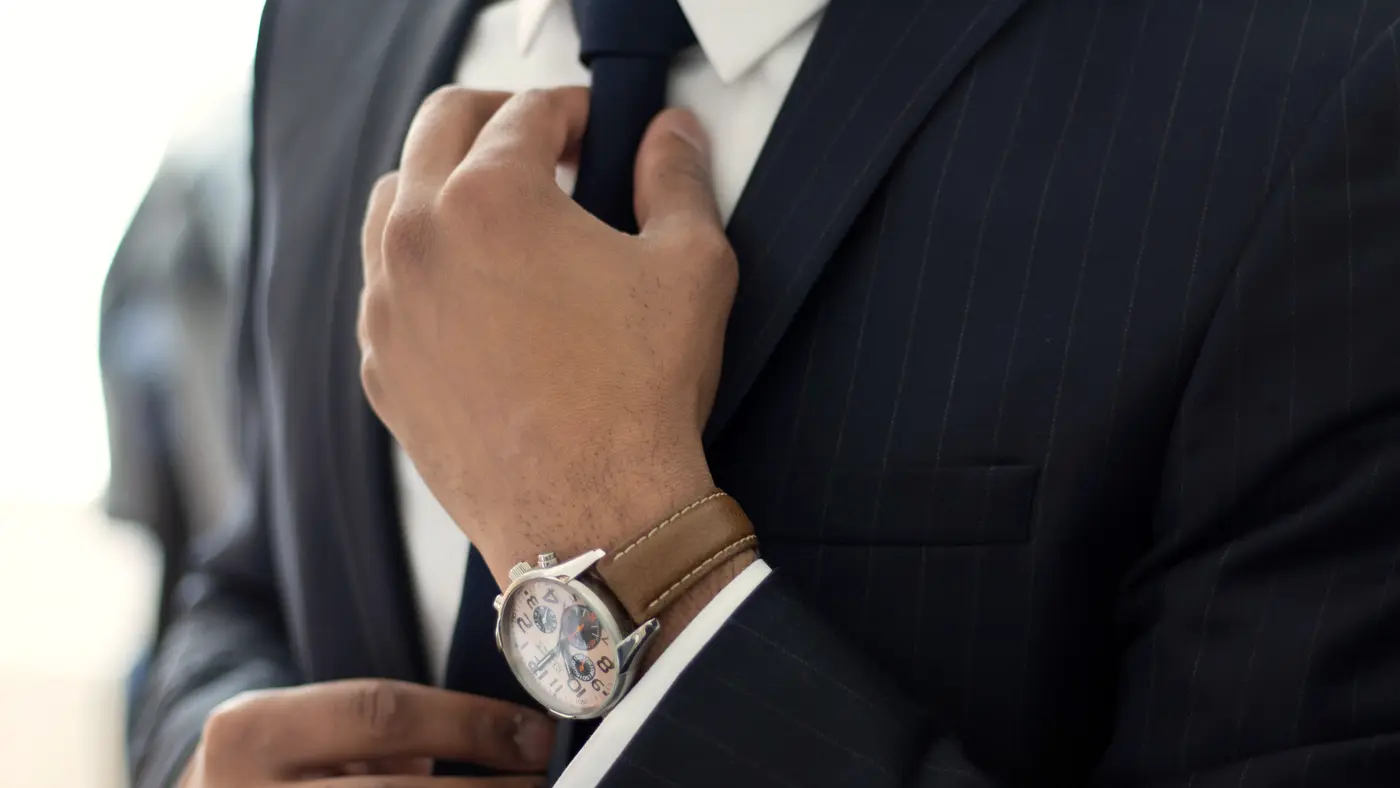 Man in a dark suit adjusting his tie